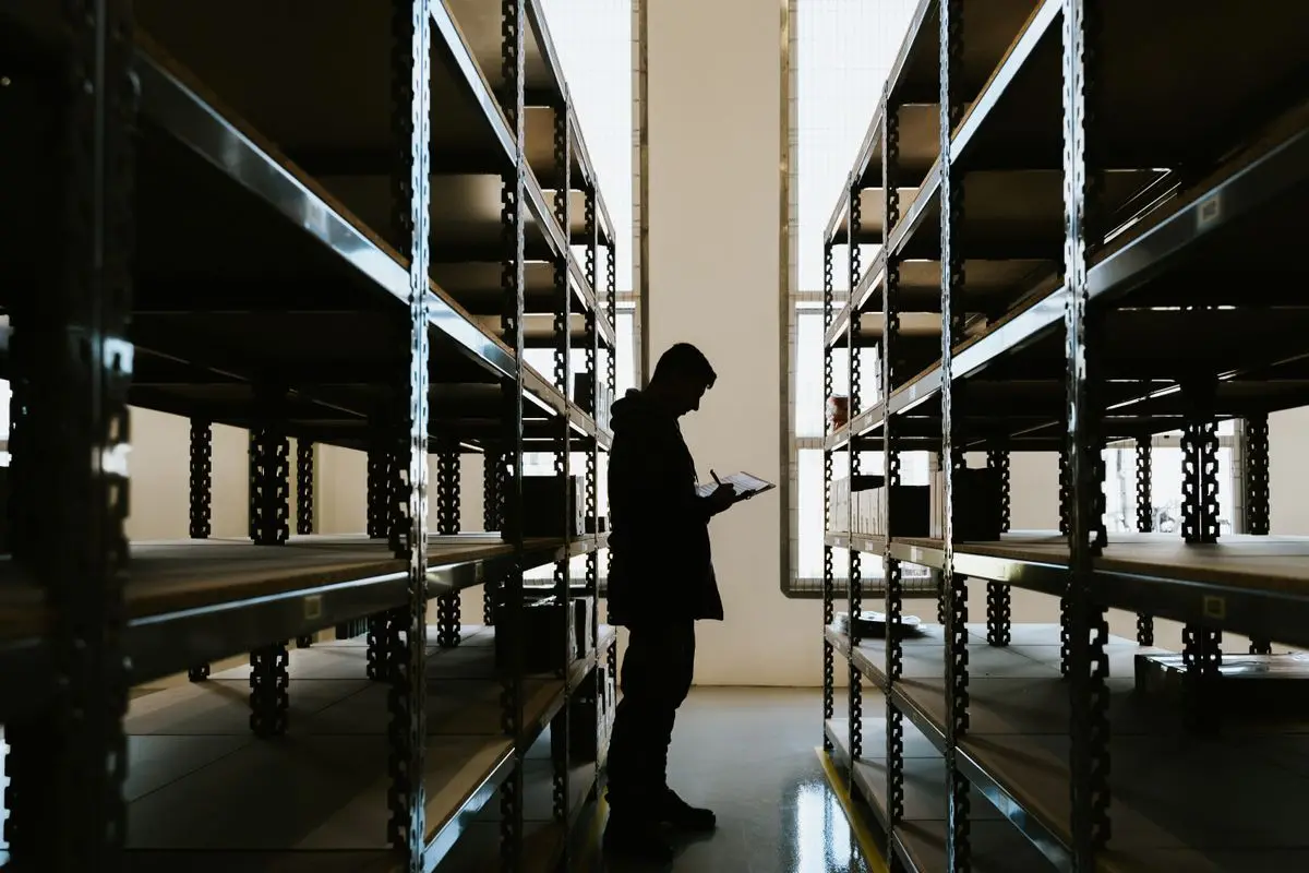 A worker between tall warehouse shelves