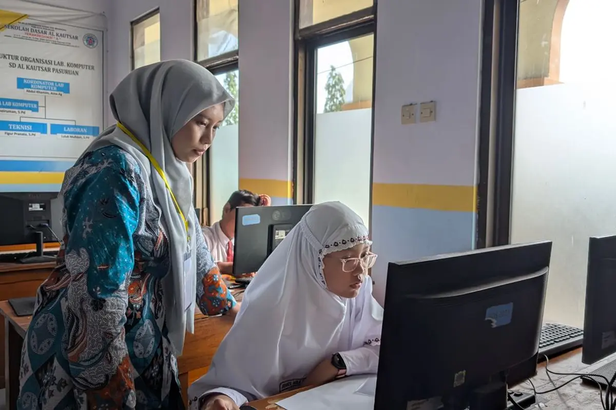 A teacher helping a student in a computer classroom