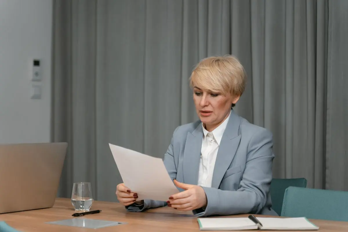 A colleague checking paperwork beside a laptop