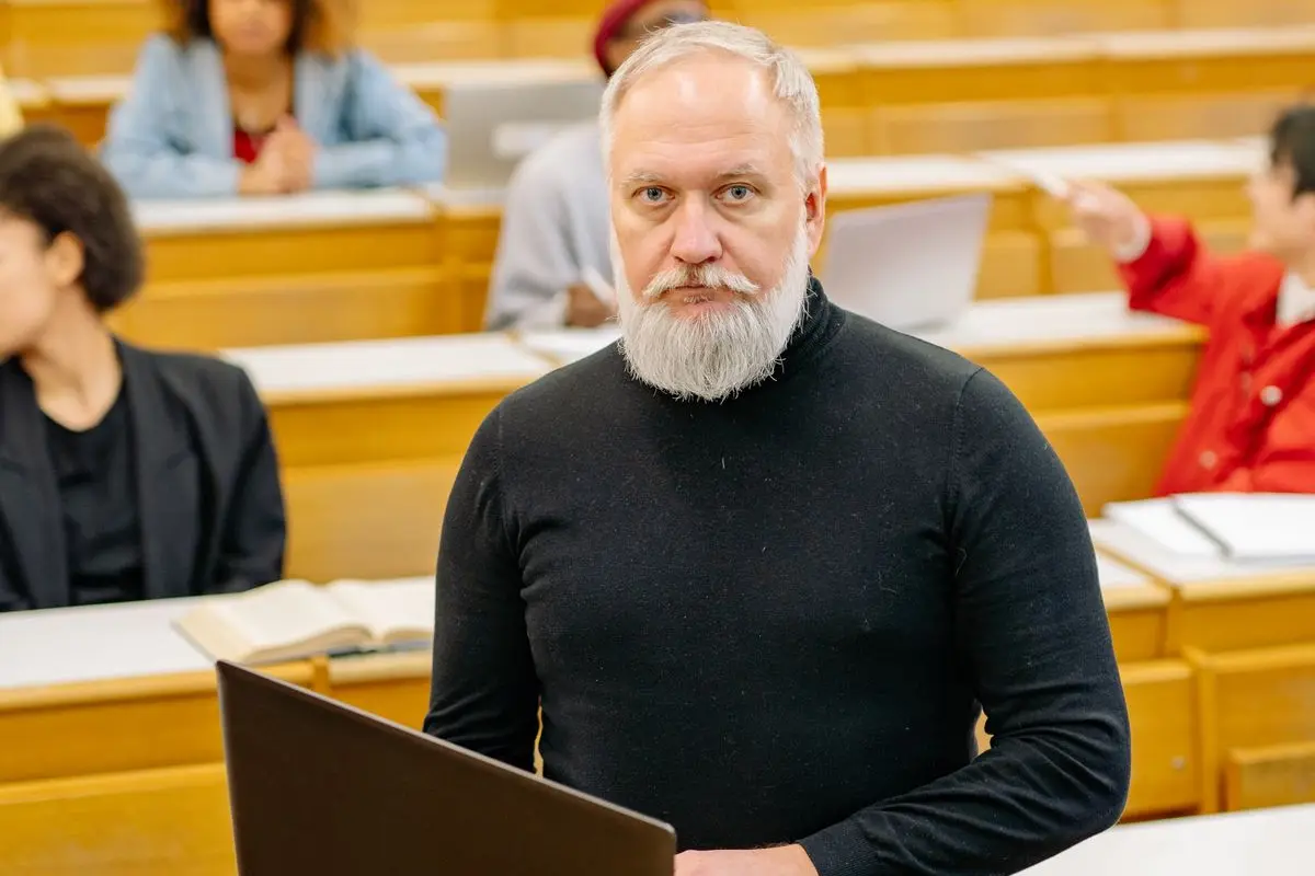 A teacher holding a laptop in a classroom